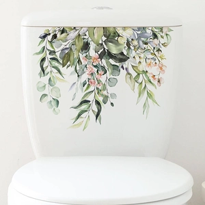 Detail of watercolor green leaves and floral decals on a white bathroom toilet tank