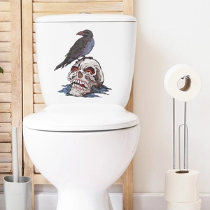 Halloween toilet sticker with black crow and red-eyed skull on a white ceramic tank