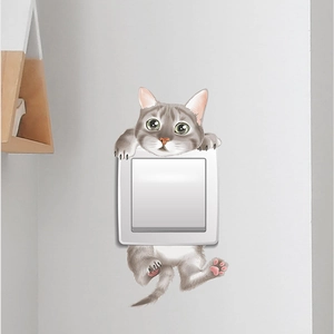 Dettaglio di un adesivo da parete con gatto grigio su una placca di interruttore bianca