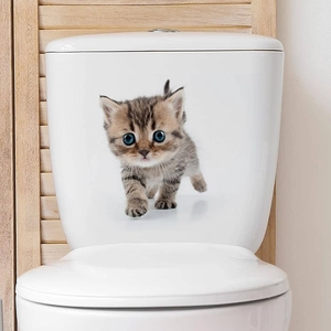 Close-up of a cute kitten wall sticker on a white ceramic toilet tank in a bathroom