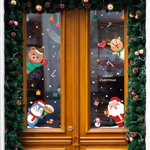 Christmas window stickers with Santa Claus and reindeer on a glass door with wreaths