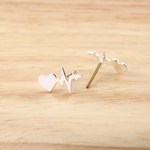 Minimalistische Herzschlag-Ohrstecker in glänzendem Silber auf einer Holzoberfläche