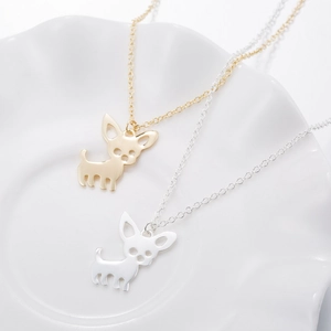 Cute Chihuahua pendant necklaces in gold and silver finish on a white ceramic plate