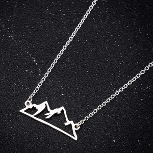 Elegant silver stainless steel mountain peak pendant necklace on a textured black backdrop