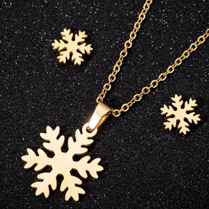 Elegantes Set aus goldener Schneeflocken-Halskette und Ohrsteckern auf schwarzem Grund
