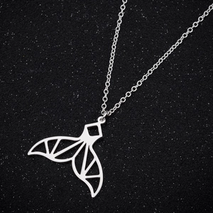 Detail shot of a silver geometric mermaid tail pendant on a shimmering dark background