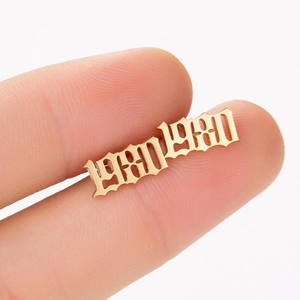 Close-up of golden gothic year 1980 stud earrings held by hand on white backdrop