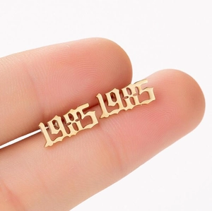 Macro shot of gold-plated 1985 birth year stud earrings in gothic style font