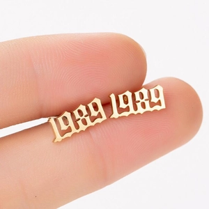 Close-up of gold 1989 gothic number earring held between fingers showing its fine size
