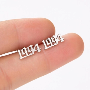 Macro shot of a silver 1994 gothic year stud earring on a finger showing its small size