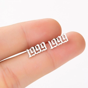 Macro shot of silver 1999 year number stud earring held by fingers to show scale and detail