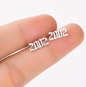 Macro shot of silver gothic 2002 birth year stud earrings held between fingers