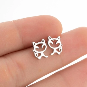 Detalle de pendientes con forma de gato plateado mostrados en la mano para escala