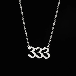Macro detail of gothic style silver 333 angel number pendant on a fine link chain