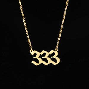 Detailed close-up of golden number 333 pendant necklace on a sleek black background