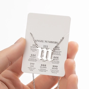 Detailed shot of silver stainless steel angel number necklace on descriptive white card