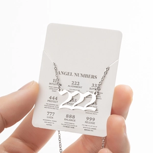 Macro shot of polished silver stainless steel 222 angel number pendant on gift card