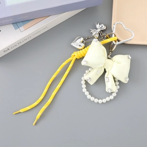 Detail view of yellow woven rope with satin bow and pearl ring charm on heart buckle