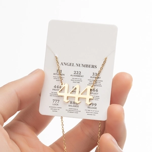 Macro shot of gold angel number 444 pendant necklace on a branded display card