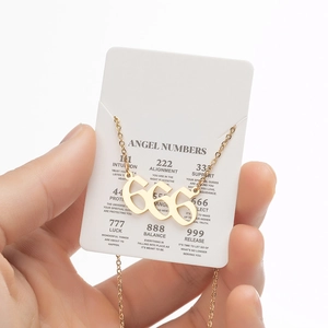 Close-up of golden 666 angel number pendant necklace on description card