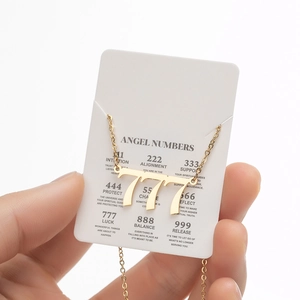 Macro shot of gold stainless steel 777 angel number pendant necklace on white display card