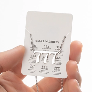 Detailed view of silver stainless steel angel number 777 pendant on white jewelry card
