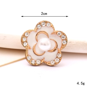 Macro detail of 2cm pearl flower charm with gold edges and sparkling rhinestones