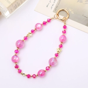 Detailed macro of pink mermaid bead phone strap with golden butterfly and spring ring