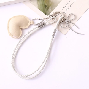 Detail of white braided leather rope and cream heart charm with silver bowknot clip