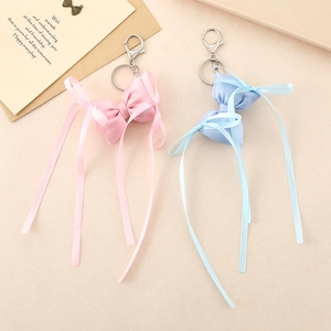 Porte-clés nœud en satin rose et bleu avec anneaux en métal argenté sur fond beige
