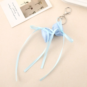 Detail of light blue silk ribbon bow keychain with silver lobster clasp on a textured background
