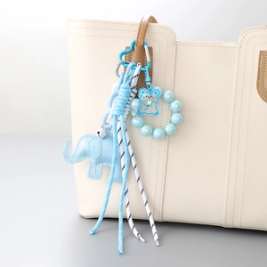 Portachiavi elefante blu in pelle con perline e nappa su una borsa tote beige