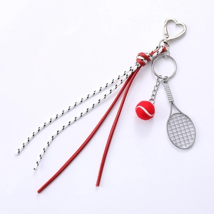 Tennis racket keychain with red ball and woven rope tassels on a white background