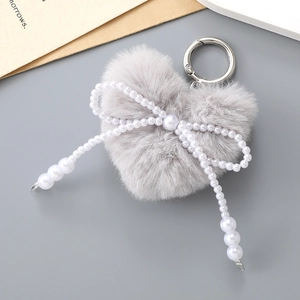 Détail d'un porte-clés en peluche cœur avec un nœud en perles et un anneau en argent
