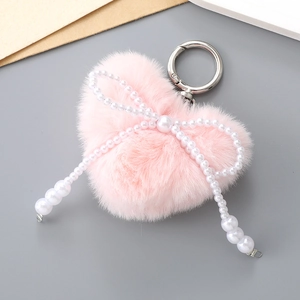 Détail d'un porte-clés coeur en peluche rose clair avec nœud en perles et anneau