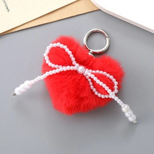 Détail d'un porte-clés cœur en fausse fourrure rouge avec nœud en perles et anneau argent