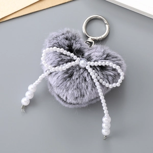 Gros plan sur porte-clés cœur en peluche grise avec nœud en perles et crochet argenté
