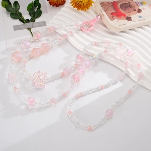 Detail of pink acrylic beaded phone charm strap with bow pendant and iridescent heart beads