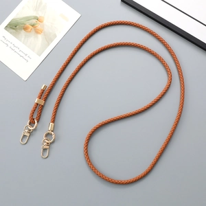 Detail of adjustable brown braided leather strap with gold hardware on blue background