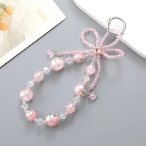Pink beaded phone charm with crystal bow and butterfly pendant on deep grey background