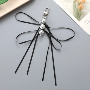 Detail of creative dragonfly bag charm with silver beads and black ribbon bow design