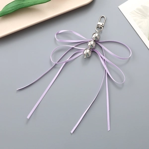 Detail of silver beads and lilac ribbon bow charm with metallic spring hook for bags