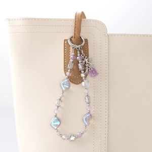 Purple crystal beaded bag charm with metal rose and butterfly on a white leather bag