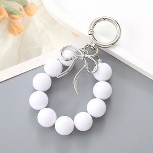 Detail view of pearl beaded keychain with silver metal bow charm and round clasp