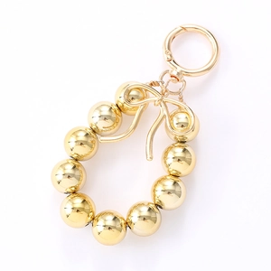 Fashionable gold beaded keychain charm with metallic bowknot on a white background
