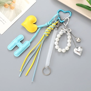 Détail de charms en cuir bleu et jaune avec perles et mousqueton cœur sur le porte-clés
