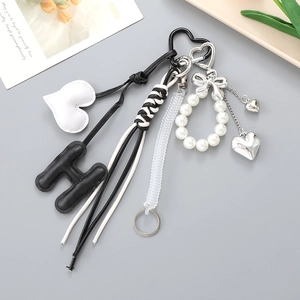 Vue détaillée du pendentif H en cuir noir et du charm de perles avec nœud ruban