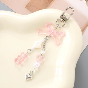 Pink resin gummy bear keychain with heart and bow charms on white ceramic tray