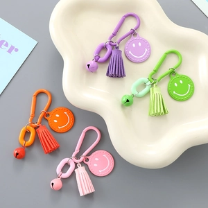 Set of colorful smiling face keychains with tassels and bells on a white display tray