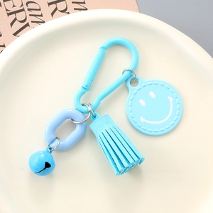 Close-up of sky blue smiley face keychain with metal carabiner and suede tassel accessory